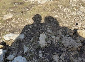 Schatten von zwei oder mehreren Personen, die zusammenstehen. Auf einer steinigen Wiese.